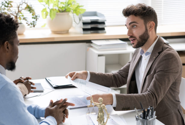 Banker consulting couple about terms and conditions of mortgage agreement in his office