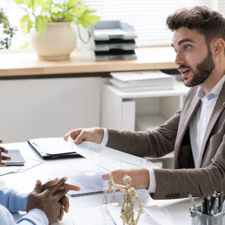 Banker consulting couple about terms and conditions of mortgage agreement in his office