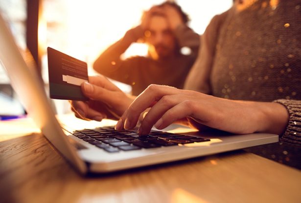 Person holding credit card making payment on laptop