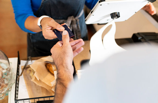 A Honor Bank customer handing over their debit card to a bakery worker.