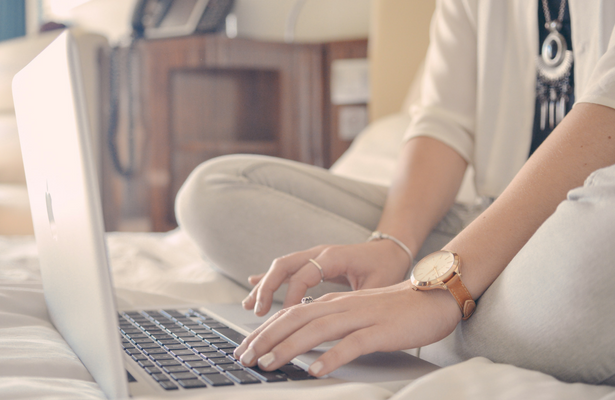 Women sitting in bed typing on a laptop