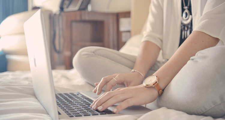 Women sitting in bed typing on a laptop