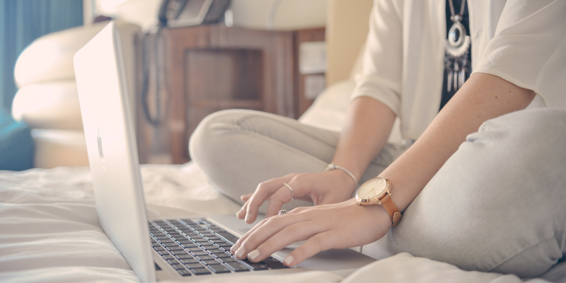 Women sitting in bed typing on a laptop