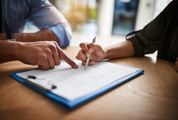 Two people sitting at table filling out mortgage documents