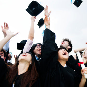 College graduate throwing graduation hats