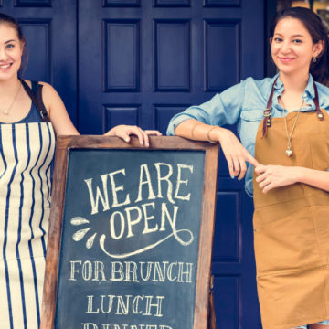 Two business owners in front of their sign