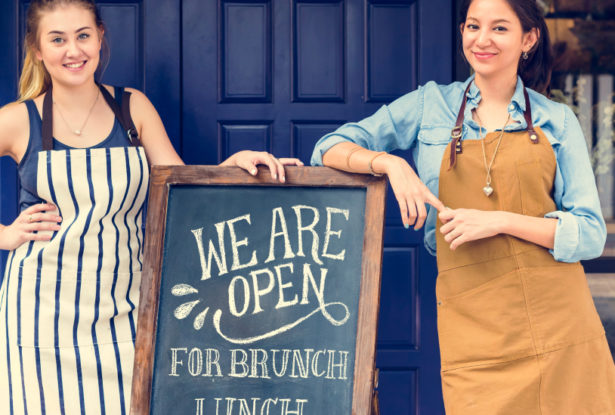 Two business owners in front of their sign