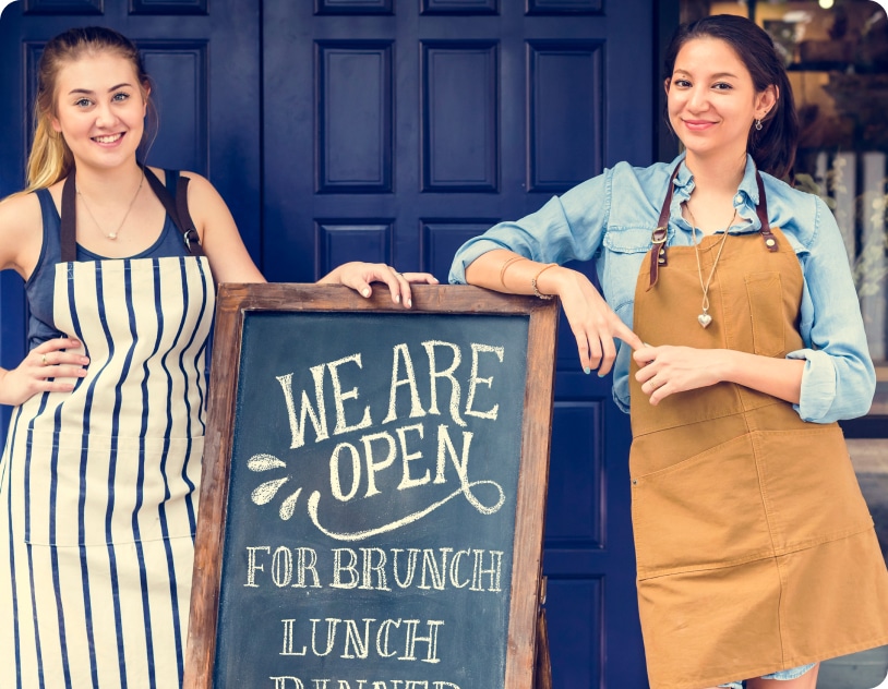 Two business owners in front of their sign