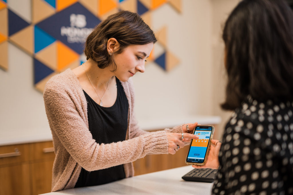 Honor Bank Employee explaining client how to use online banking app