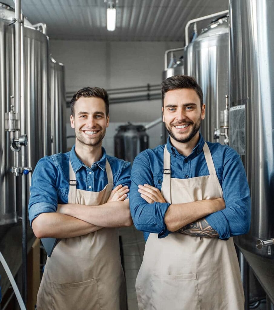 Happy employees in their workshop with metal tanks behind them