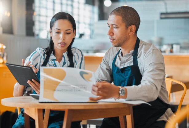 business-partners-talking-at-table-looking-through-presentation