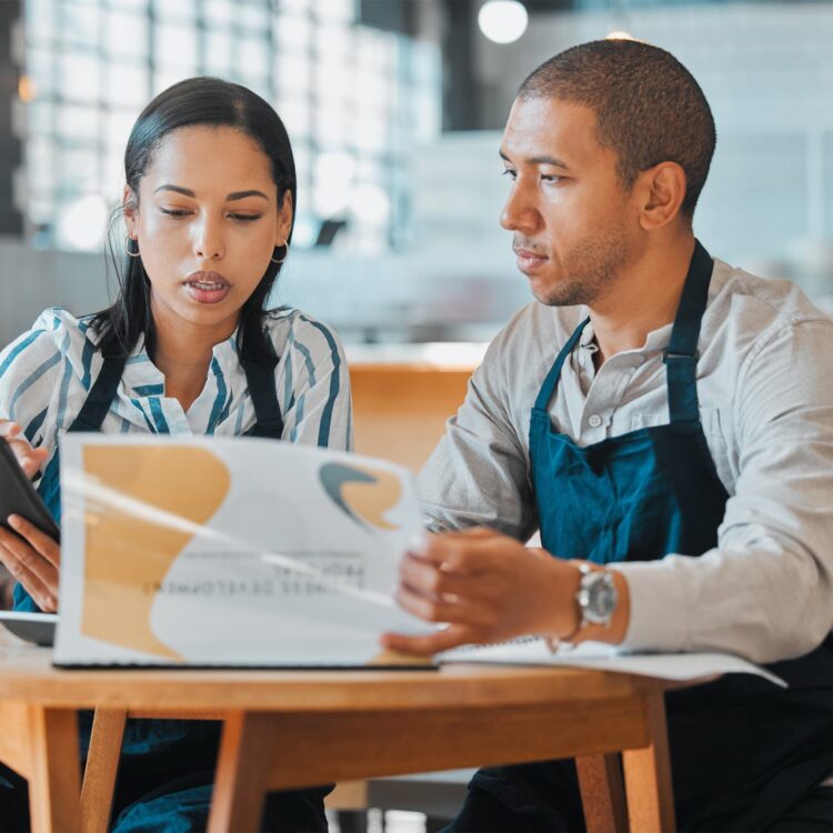 business-partners-talking-at-table-looking-through-presentation